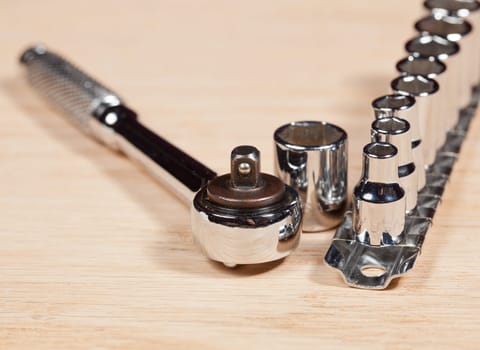 Wrench and miniature sockets in a holder on a piece of wood bench