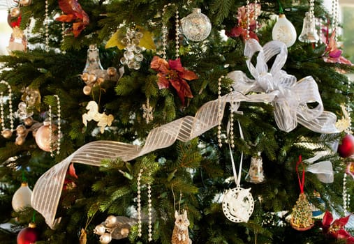 Christmas tree decorated with silver and white ribbons and ornaments in family home
