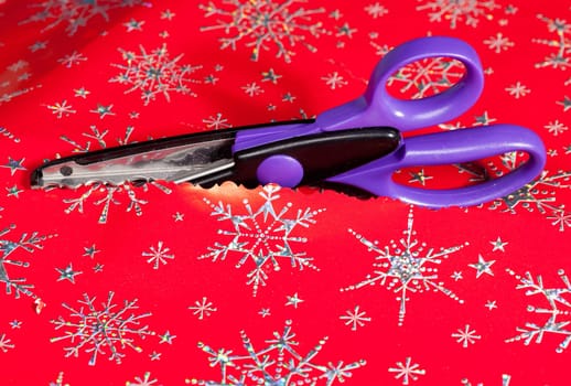 Christmas paper being cut by special scissors to create pattern in the cut edge
