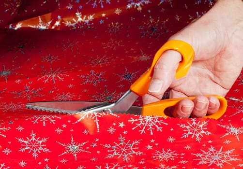 Christmas paper being cut by special scissors to create pattern in the cut edge