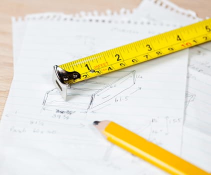 Tape measure and pencil laying on plans for a woodworking project
