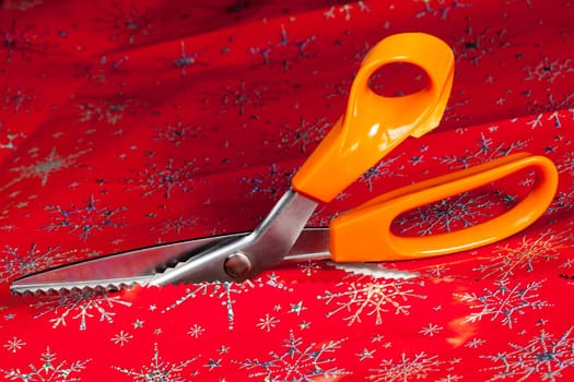 Christmas paper being cut by special scissors to create pattern in the cut edge