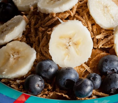 Breakfast cereal with bananas blueberries and bran flakes in bowl