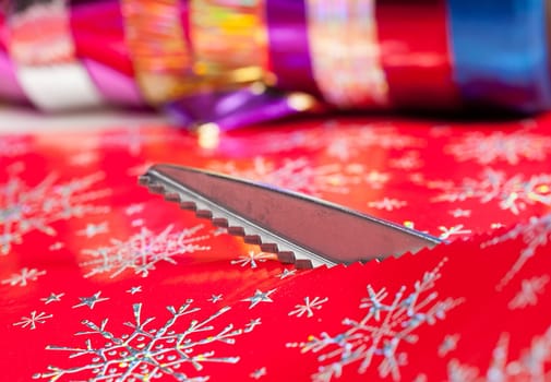 Christmas paper being cut by special scissors to create pattern in the cut edge
