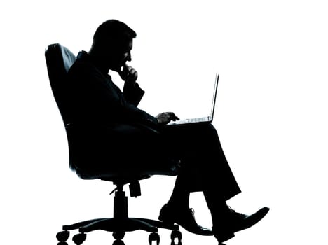 one caucasian business man computer computing sitting in armchair silhouette Full length in studio isolated on white background