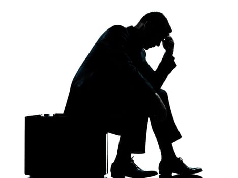 one caucasian business man sitting on suitcase tired despair silhouette Full length in studio isolated on white background