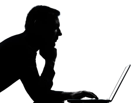 one caucasian business man computing computer laptop serious portrait silhouette in studio isolated on white background