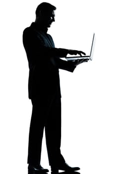 one caucasian business man computing computer laptop silhouette standing Full length in studio isolated on white background