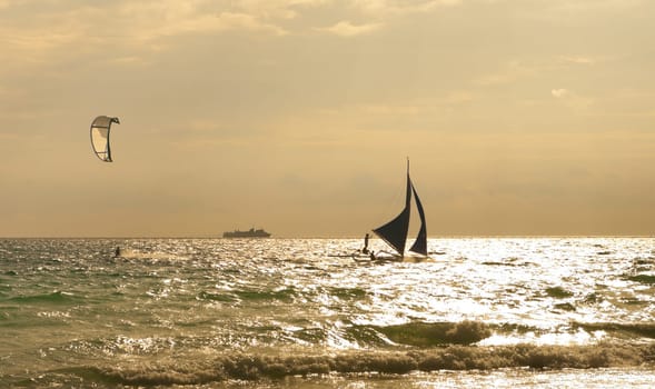 kite surfer and sailboat against a beautiful sunset