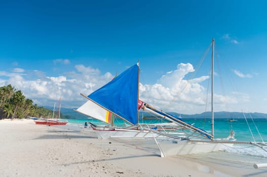 traditional paraw sailing boats on the famous white beach on Boracay island, Philippines