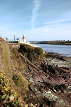 lighthouse during a sunny day on the rocks in with steps to beach in youghal county cork ireland