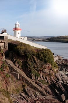 lighthouse during a sunny day on the rocks in with steps to beach in youghal county cork ireland
