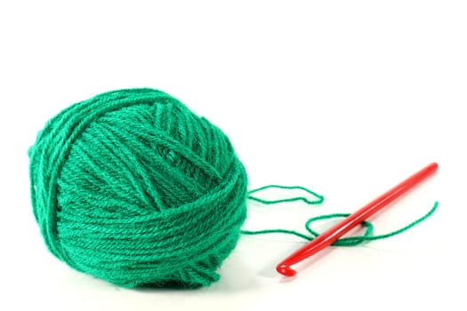 a ball of wool with crochet hook against a white background