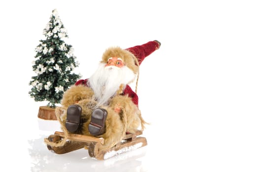 Miniature of Santa Claus on sleigh and a pine tree with snow, on white reflective background.