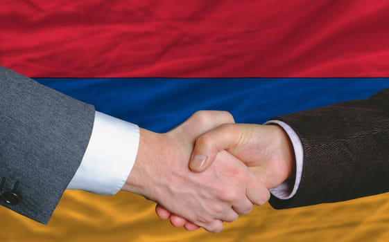 businessmen handshake after good deal in front of armenia flag