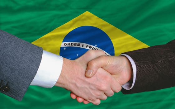 businessmen handshake after good deal in front of brazil flag