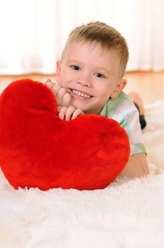 the child is lie on the floor with a red plush heart