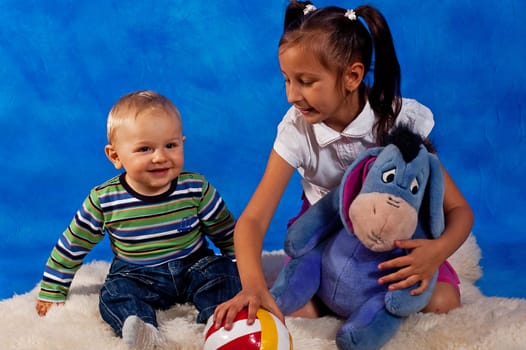 two children playing with toys against the blue mosaic background