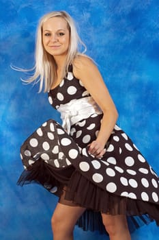 beautiful girl on the blue mosaic background in a polka-dot-dress