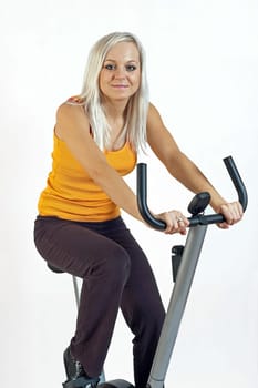 young woman riding a fitness bicycle isolated against a white background.