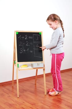 Cute girl doing the math on chalkborard
