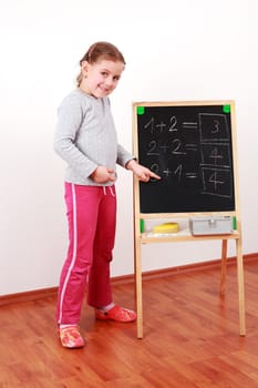 Cute girl doing the math on chalkborard