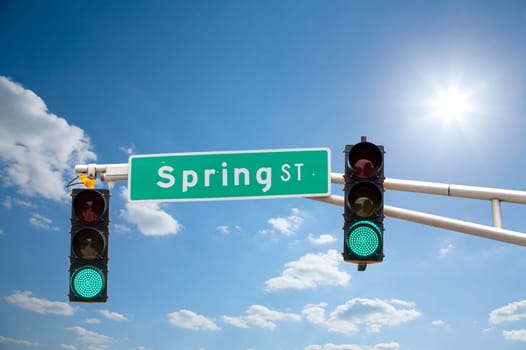 Image of a street sign and traffic lights with blue sunny skies in the background