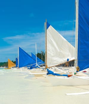 traditional paraw sailing boats on white beach on boracay island, Philippines