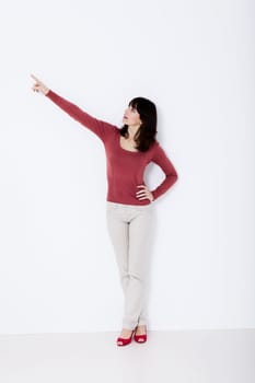 Beautiful woman standing and pointing up. Studio shot.