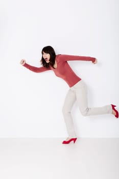 Beautiful woman running and shouting. Studio shot.