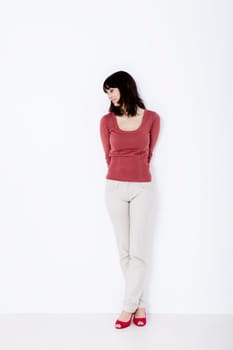 Beautiful woman standing and looking down. Studio shot.