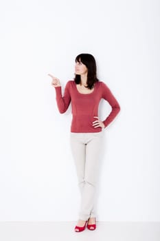 Beautiful woman standing and pointing up. Studio shot.