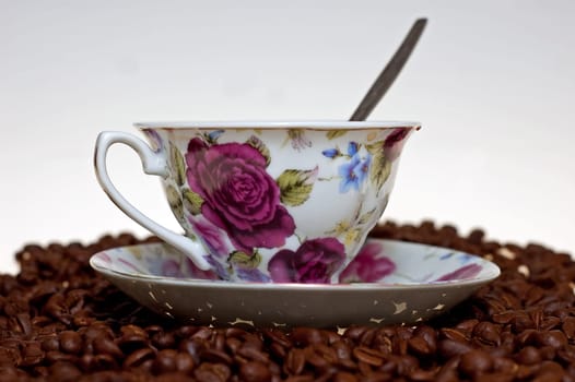 A cup in a pile of coffe beans on white background.