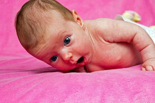 Baby lying on her tummy and a pink blanket