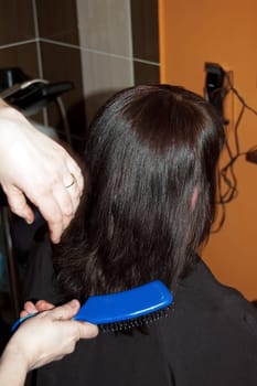 Stylist work on woman hair in salon