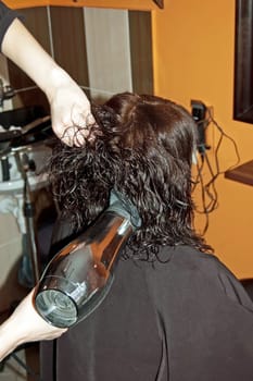 Stylist work on woman hair in salon