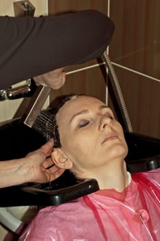 Stylist work on woman hair in salon