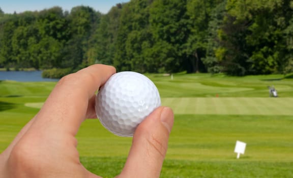 Hand Holding Golf Ball - Golf Green With Flag in Background