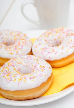 Donuts With Colorful Sprinkles, Plates and Mugs on Table - Shallow Depth Of Field