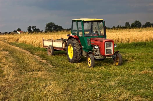 An old farm tractor on the side of an agriculture field in South Poland