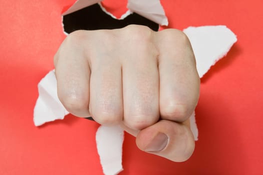 aggression and violence . Hand punching through red paper