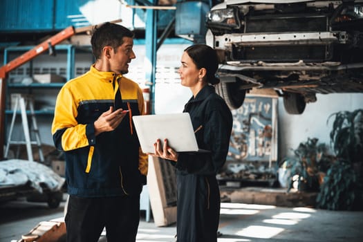 Two vehicle mechanic working together, conduct car inspection with laptop. Automotive service technician in uniform carefully make diagnostic troubleshooting to identify error. oxus