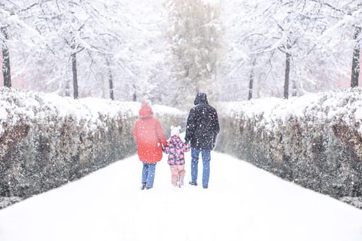 Rear view of happy family with child in winter park. High quality photo