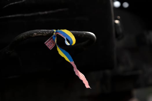 A ribbon with a Ukrainian blue and yellow flag attached to military equipment, a concept on the theme of the war and events in Ukraine, close-up view.