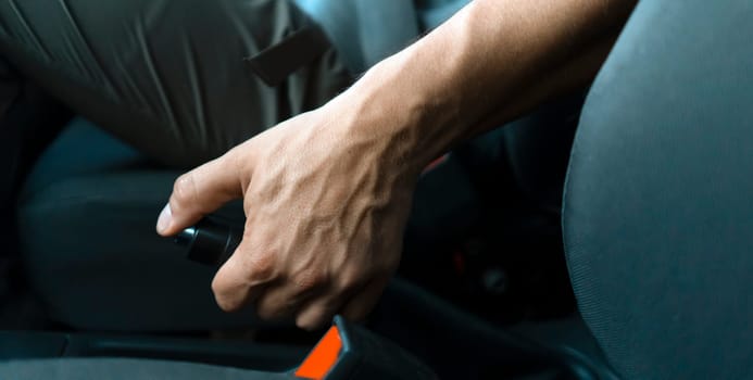 A man drives his car, slows down, keeps his hand on the handbrake and makes parking, hand close-up.