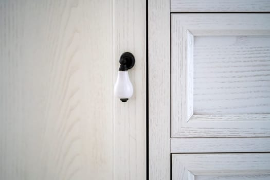 Doors and fittings of a vintage wooden cabinet or wardrobe closeup view, white-painted wood in a modern classic style.