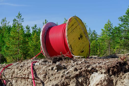 Wooden Reel with High Voltage Red Cable in Forest: Ready for Underground Power Line Installation, in forest