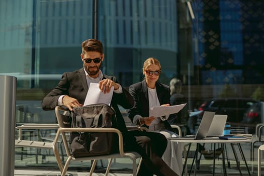 Business colleagues working with documents sitting outside of office on cafe terrace