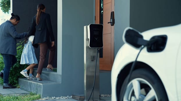 Concept of a progressive family with a home charging station for an electric vehicle, encouraging healthy and clean environment. The electric vehicle powered by sustainable, clean energy technology.