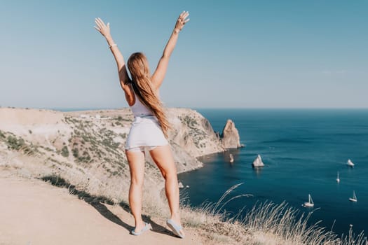 Woman travel sea. Young Happy woman in a long red dress posing on a beach near the sea on background of volcanic rocks, like in Iceland, sharing travel adventure journey